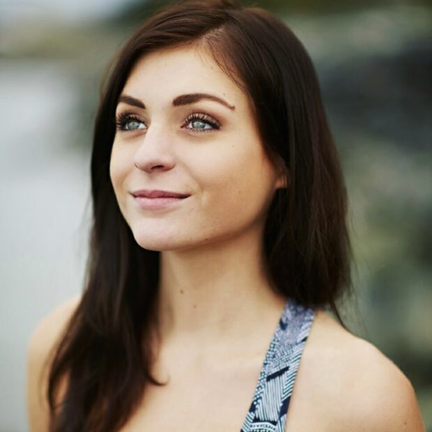 A young woman with long dark hair and blue eyes smiles slightly.